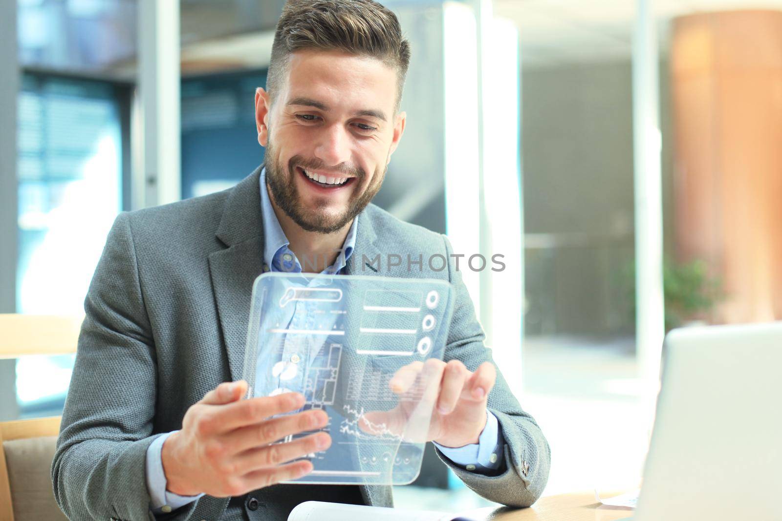 Future concept. Businessman analyzing financial statistics displayed on the futuristic transparent tablet screen