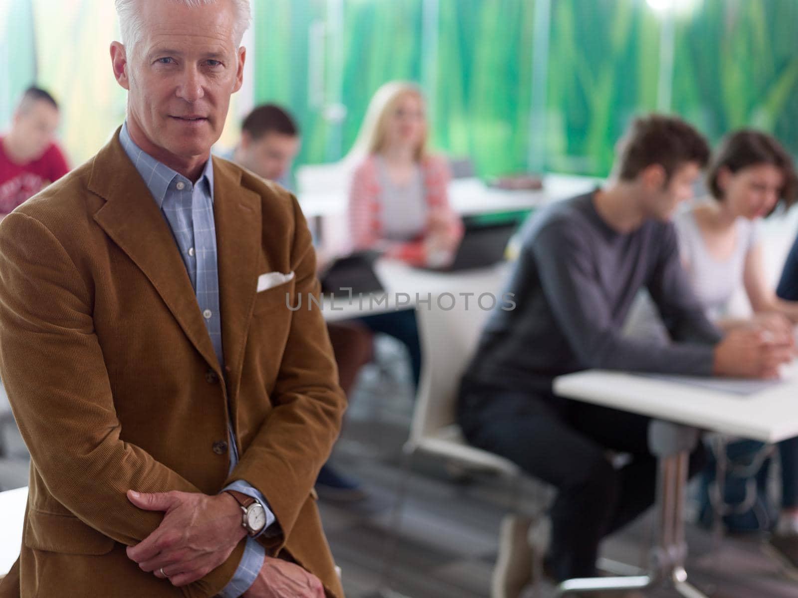 portrait of in teacher in classroom with students group in background by dotshock