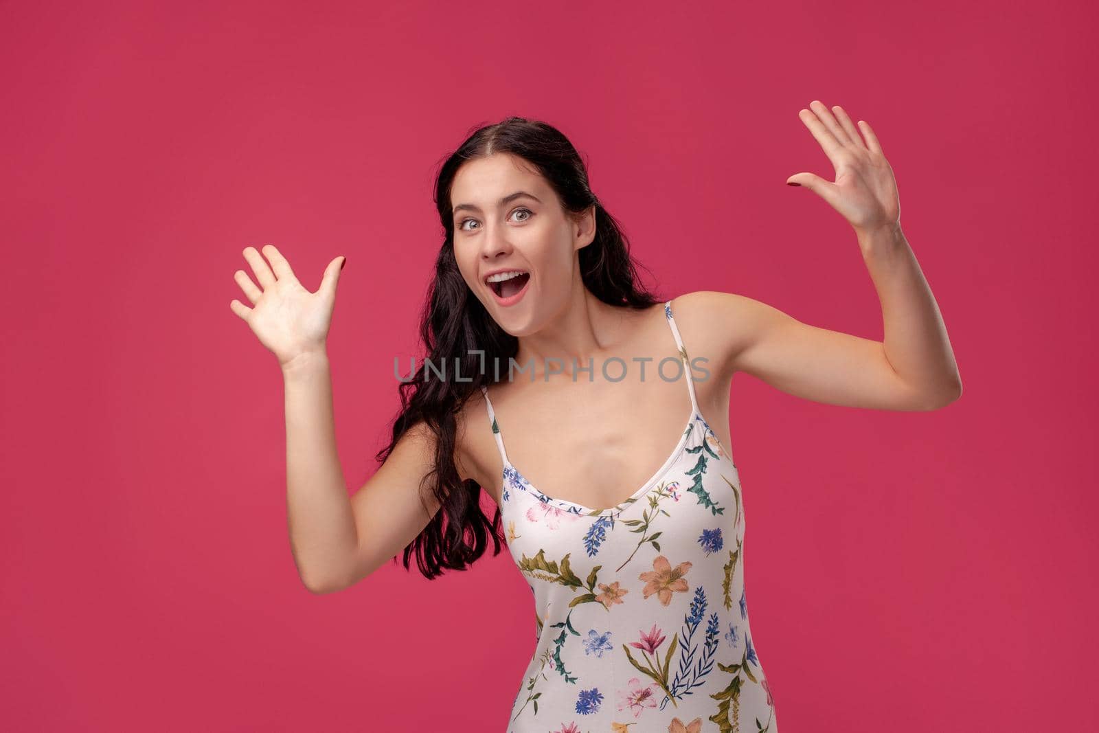 Portrait of beautiful happy young brunette woman and greeting gesture on the pink background