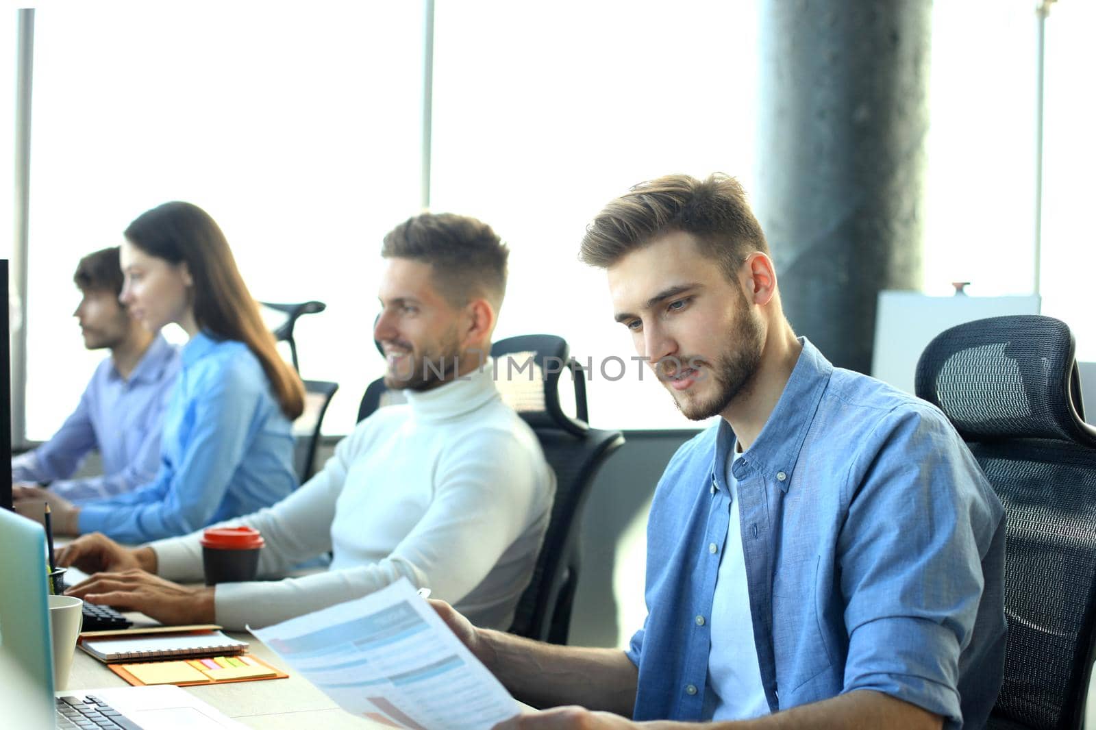 Young modern colleagues in smart casual wear working together while spending time in the creative office. by tsyhun