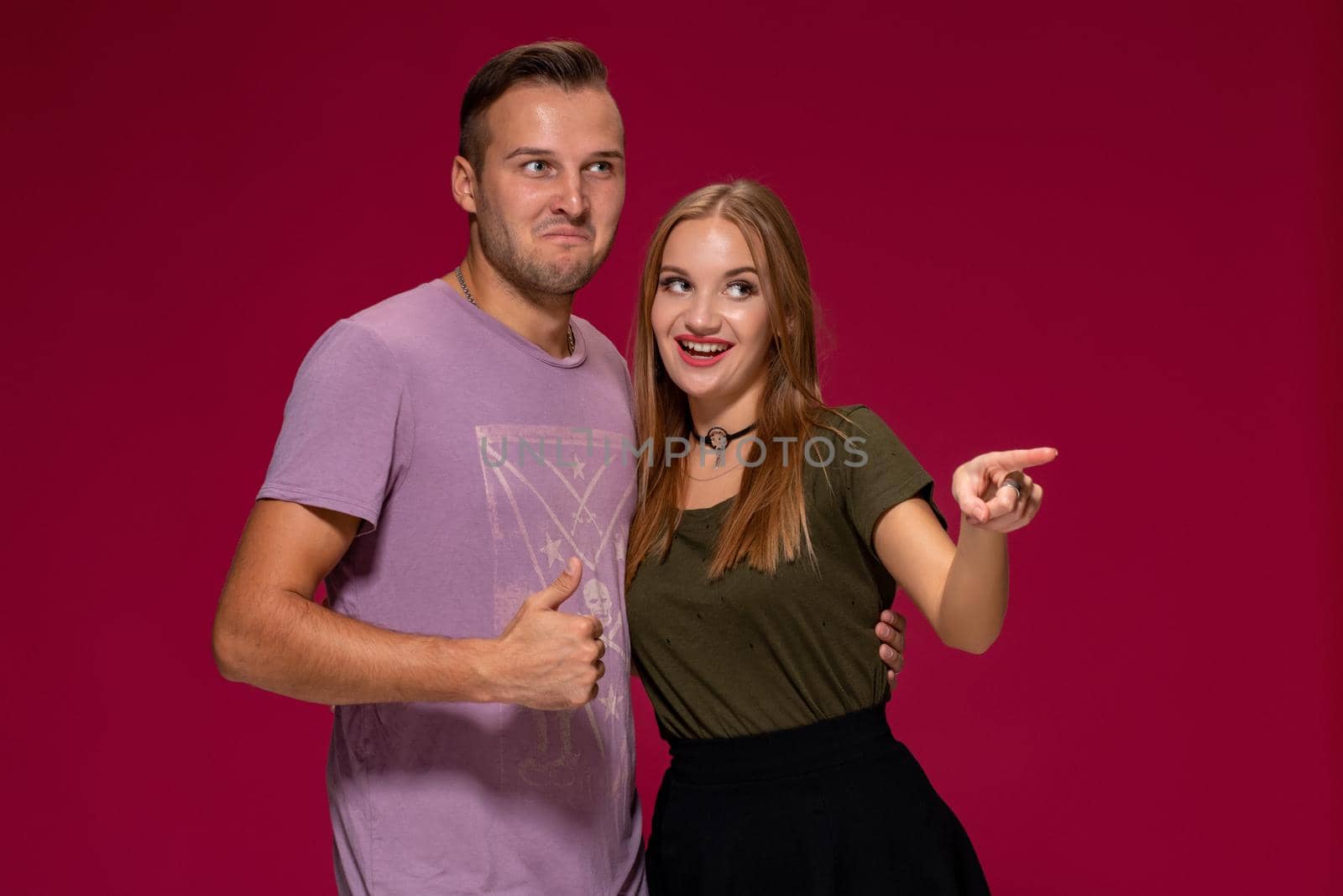 People, friendship, love and leisure concept - lovely couple with thumbs-up gesture on burgundy background with copy space for your advertisement or written text.