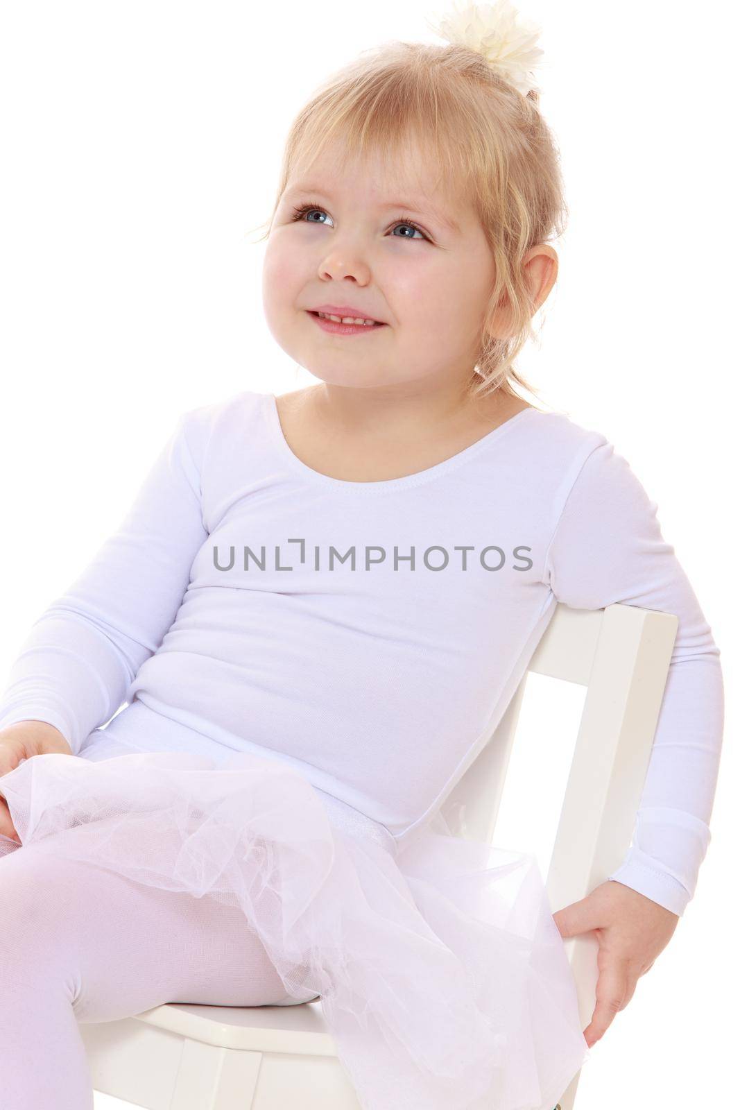 Happy little girl , a future figure skater, sits on a chair in a White sports dress , close-up-Isolated on white background