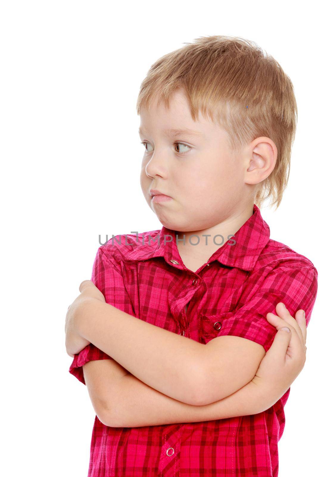 Pensive little boy in the red shirt. The boy looks to the side. Isolated on white background.