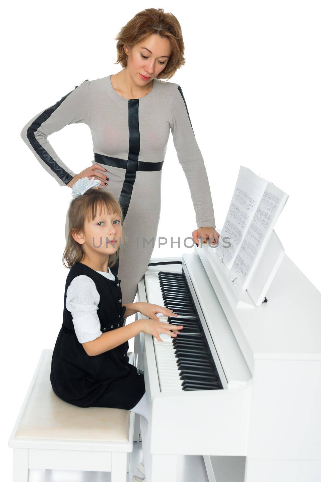 Diligent little girl at a music school teaching musical notation. Beside her is her teacher - Isolated on white background