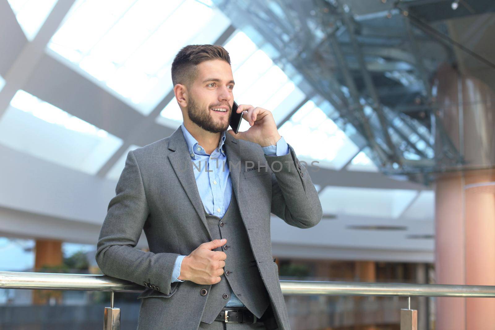 Young smiling businessman calling on phone at office