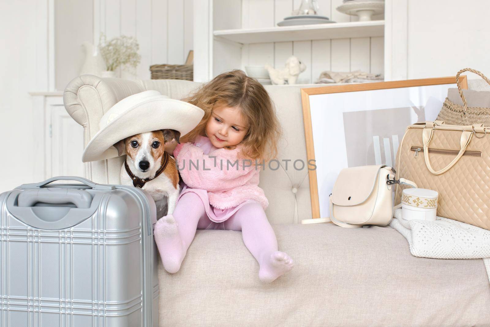 A little girl with suitcases and a dog in the interior. Holiday, Travel - family ready for the travel for vacation