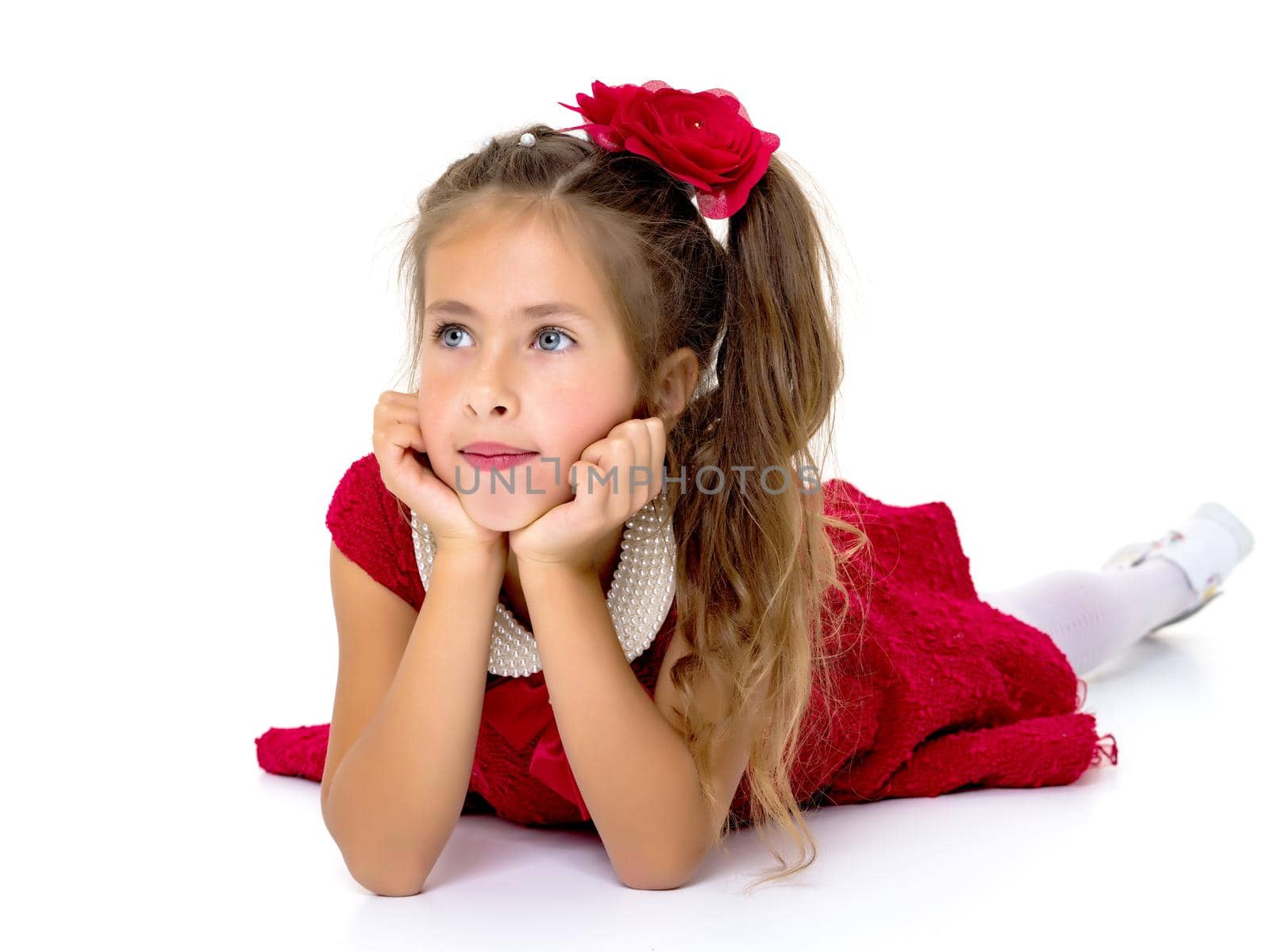 Beautiful little girl lies on the floor on a white background. The concept of a happy childhood, well-being in the family. Isolated.