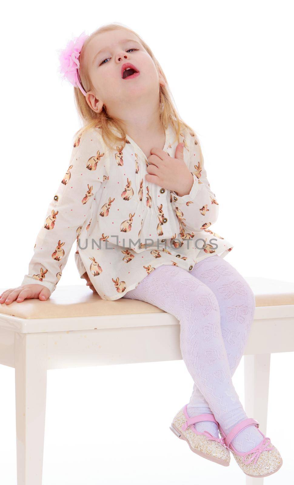 Cute little girl in shorts and white top thing with a big pink bow on her head. Girl sitting on white stools and faint from the heat - Isolated on white background