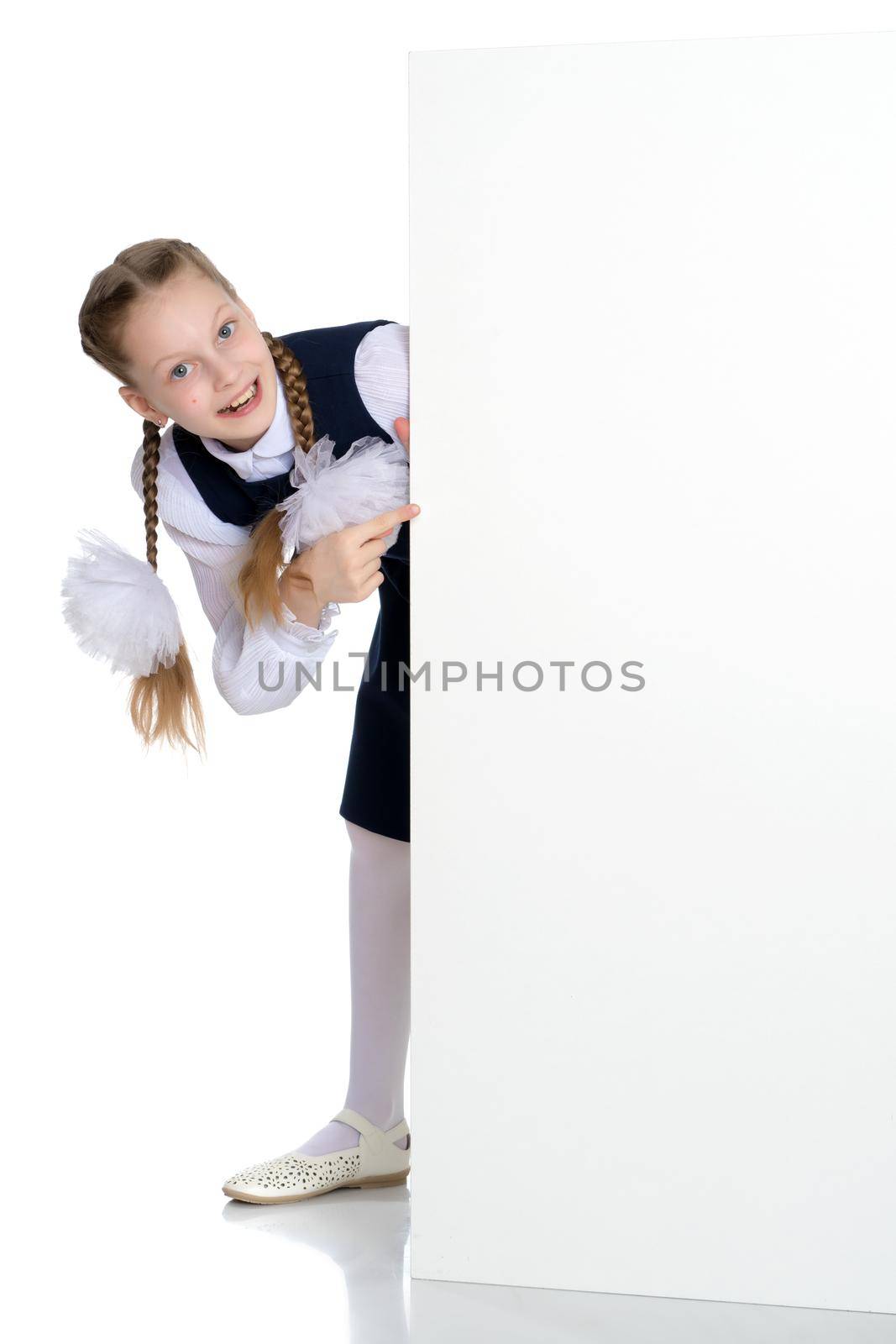A beautiful little girl points a finger at an empty white banner in which you can insert text with your company's advertisement. The concept of promoting products in the market, children's emotions. Isolated on white background.