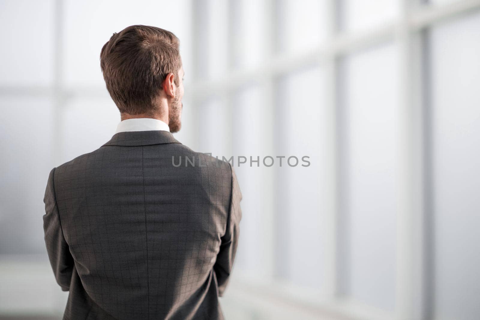 rear view.businessman standing near the office window. photo with copy space