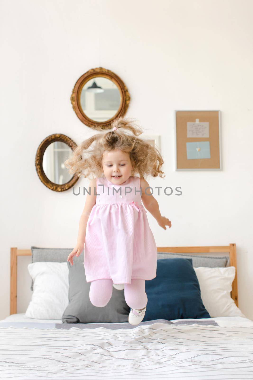 Cute little girl jumping on white bed by Demkat