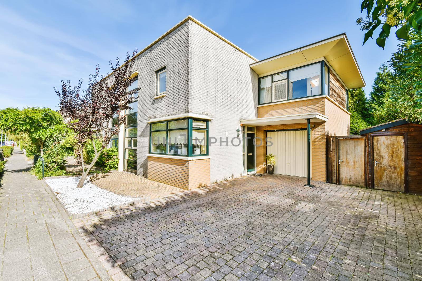 View of a two-storey pretty house with a fence of greenery