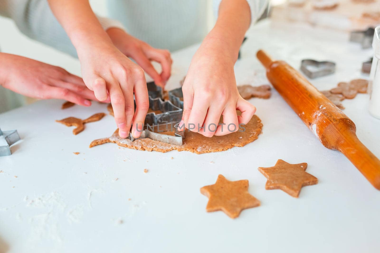 Kid's hands making gingerbread, cutting cookies of gingerbread dough. Christmas bakery. Friends making gingerbread view from above. Festive food, cooking process, family culinary, Christmas and New Year traditions concept