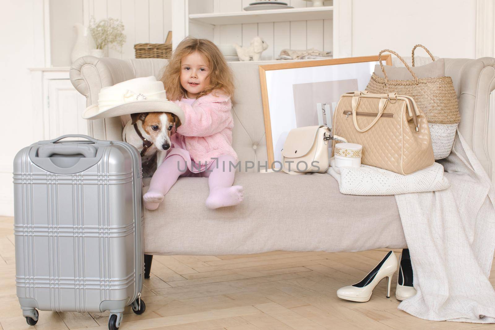 A little girl with suitcases and a dog in the interior. Holiday, Travel - family ready for the travel for vacation