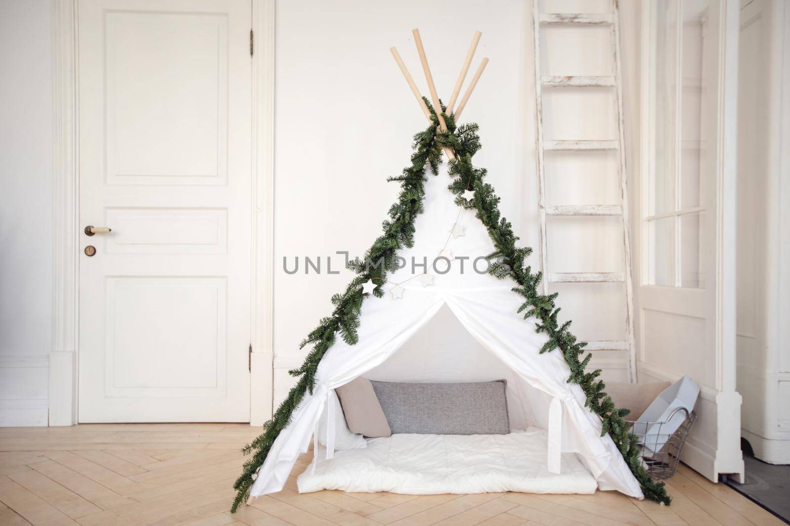 Beautiful comfortable tent with pillows inside created at home and decorated with pine branches.