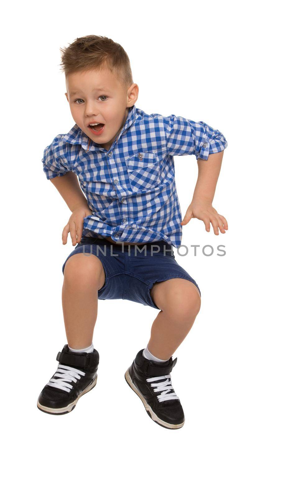 Cheerful little boy in a plaid shirt and blue shorts jumping - Isolated on white background