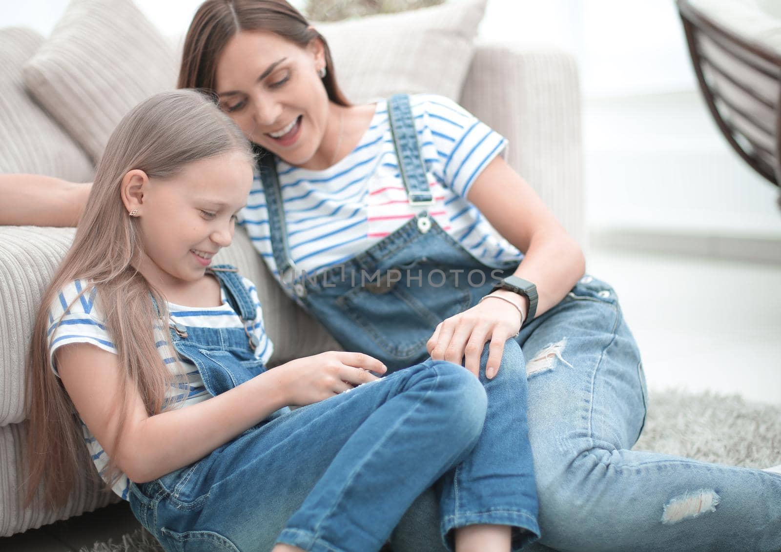 Mother with a little daughter using a smartphone sitting in the new living room.people and technology