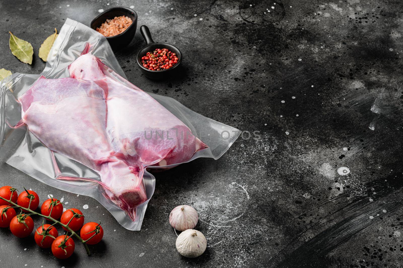Fresh turkey legs vacuum pack with ingredients set, with copy space for text, on black dark stone table background