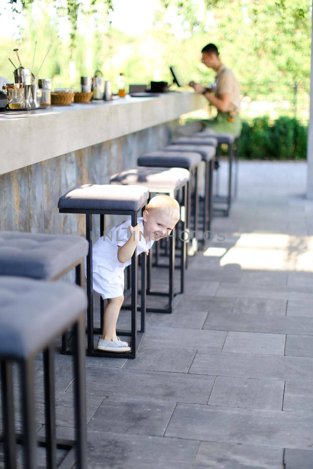 Little pretty male baby playing outside at street cafe. by sisterspro