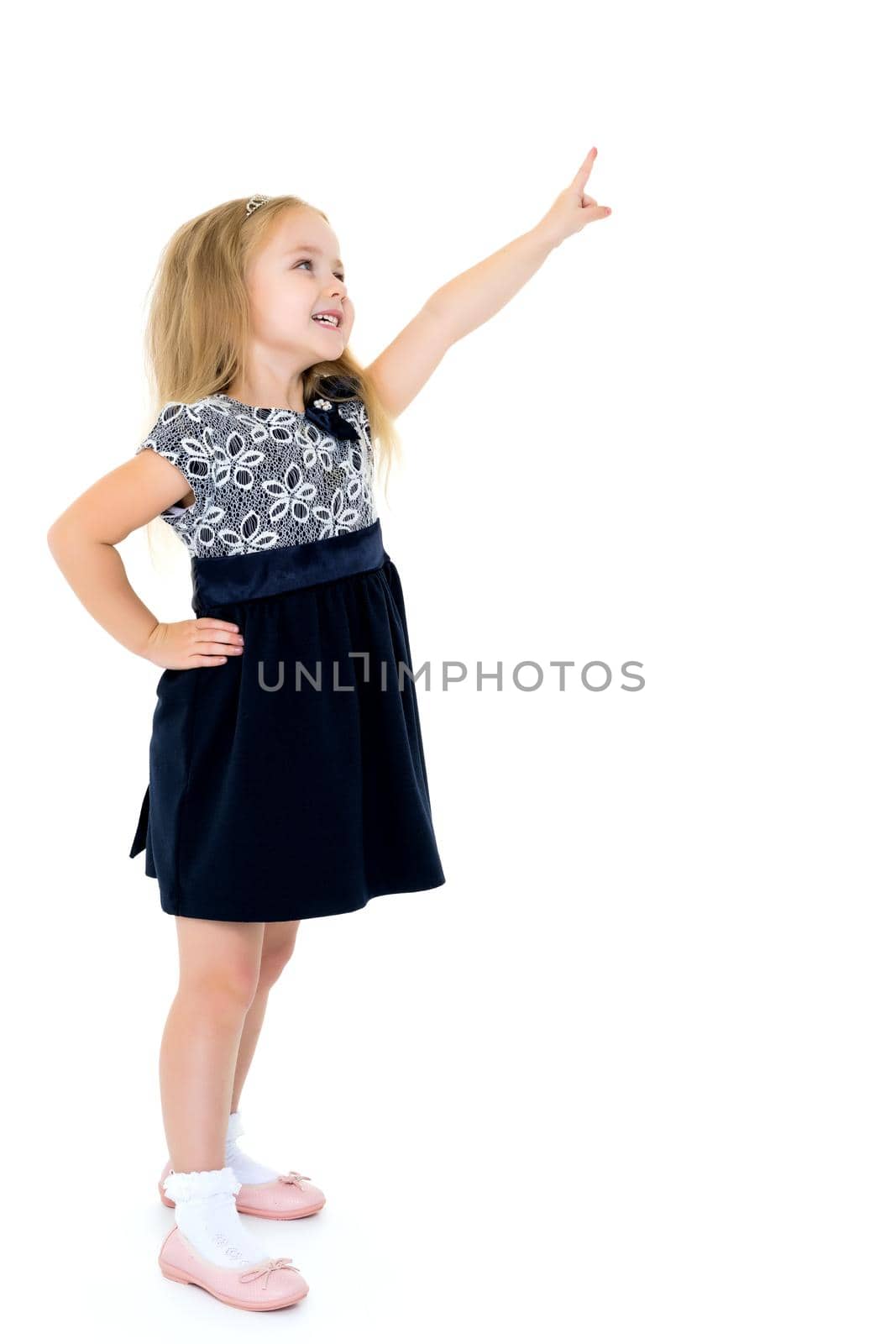 A cute little girl is attracted by attention pointing a finger at something. The concept of advertising goods and services. Isolated on white background.