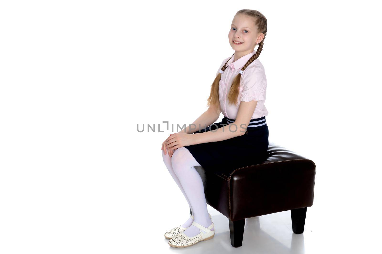 Girl schoolgirl with long pigtails sitting on the couch. by kolesnikov_studio