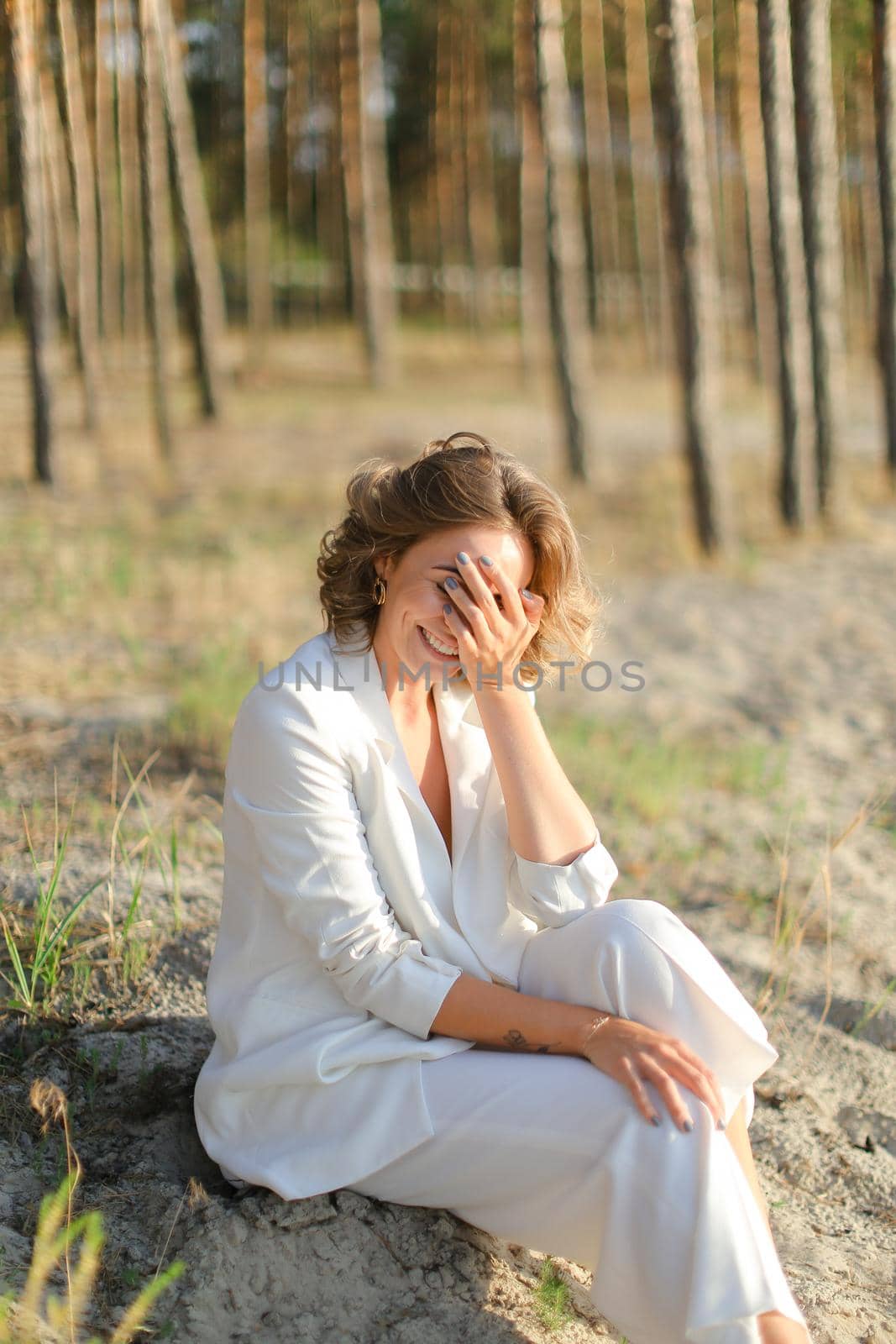 Young happy woman sitting on sand beach with trees in background. by sisterspro