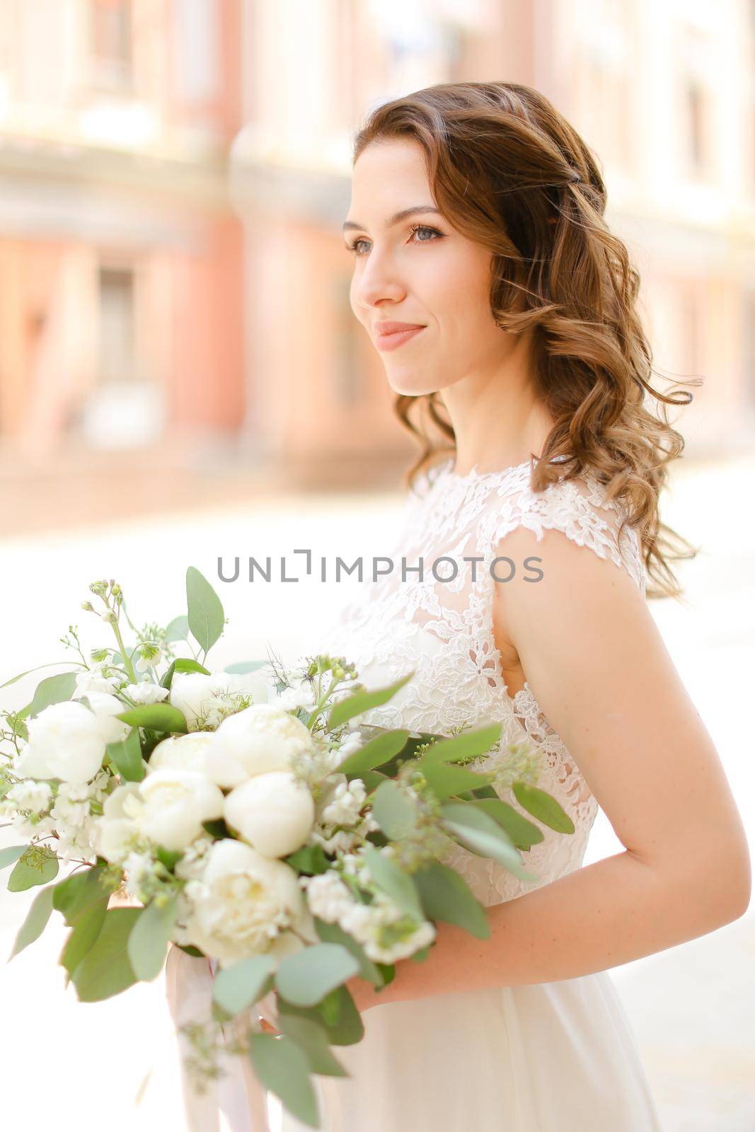 Happy caucasian bride keeping bouquet of flowers and wearing white dress. by sisterspro