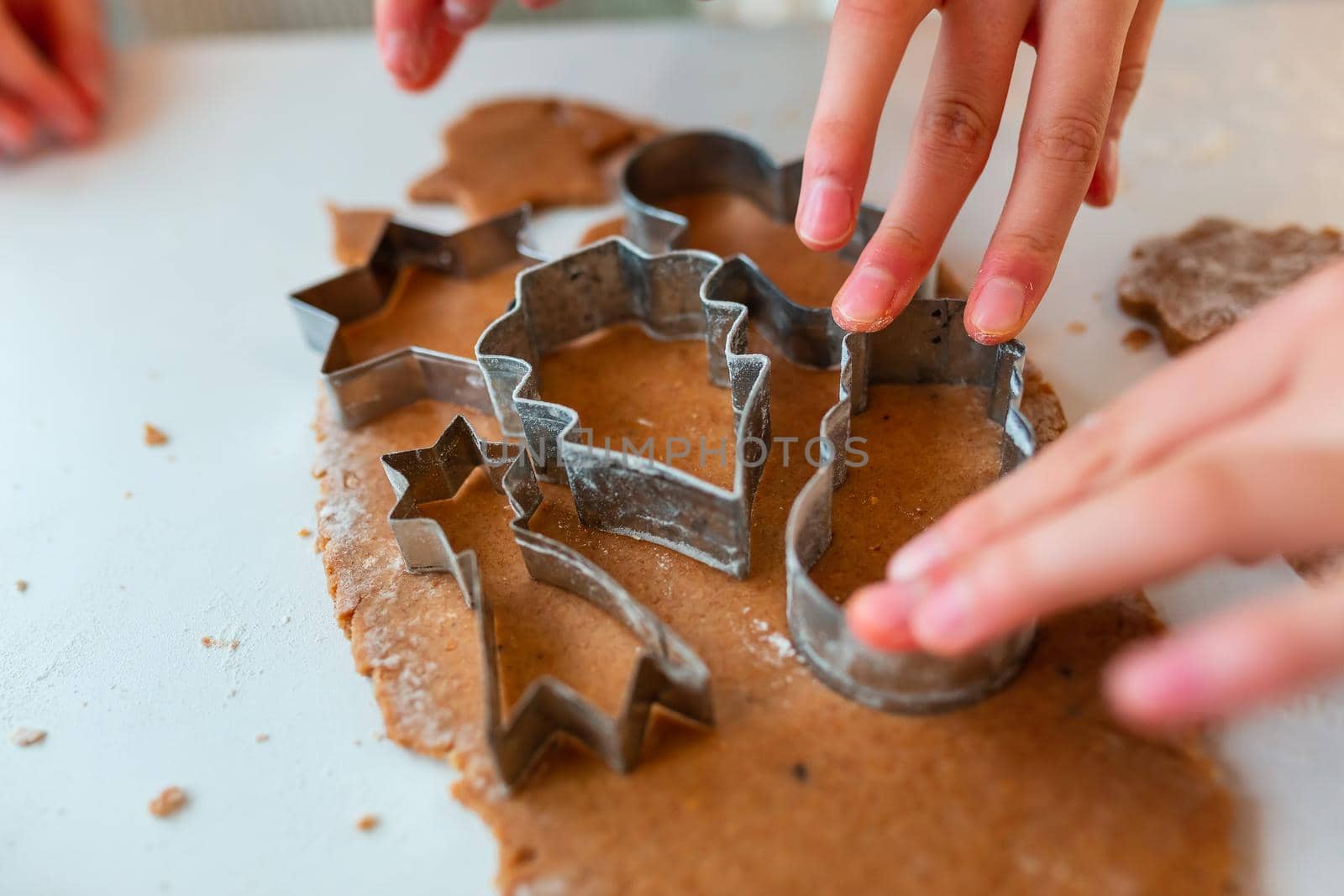 Kid's hands making gingerbread, cutting cookies of gingerbread dough. Christmas bakery. Friends making gingerbread view from above. Festive food, cooking process, family culinary, Christmas and New Year traditions concept