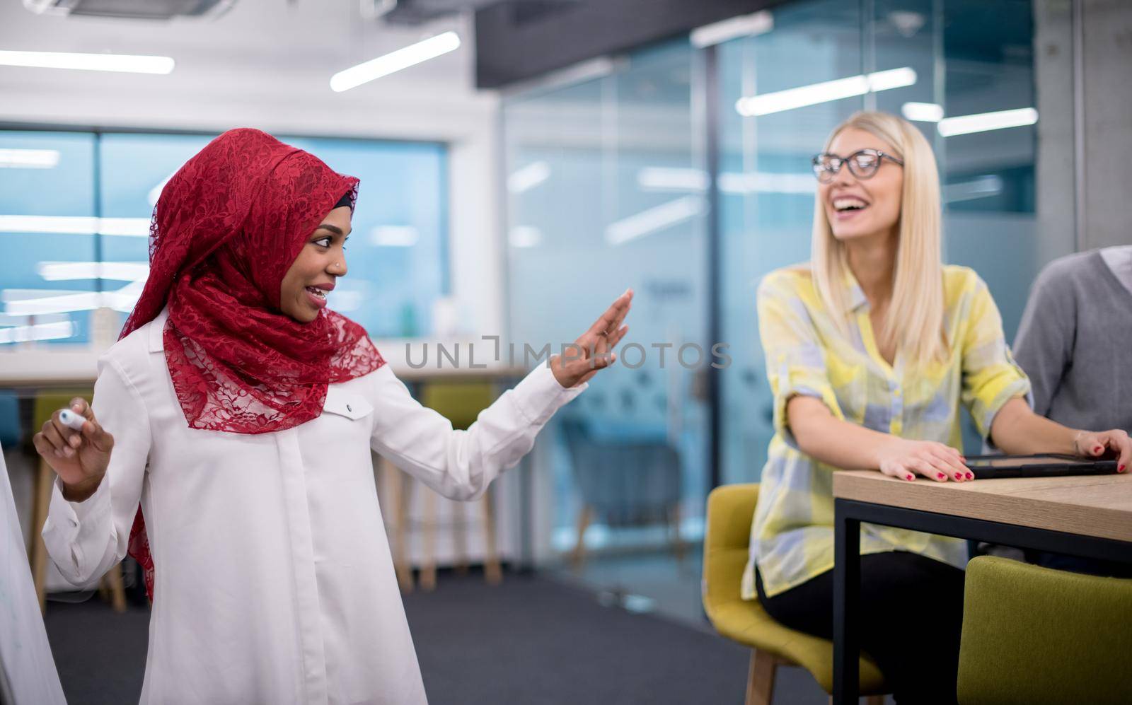 young black muslim businesswoman giving presentations to her multiethnic business team at modern startup office