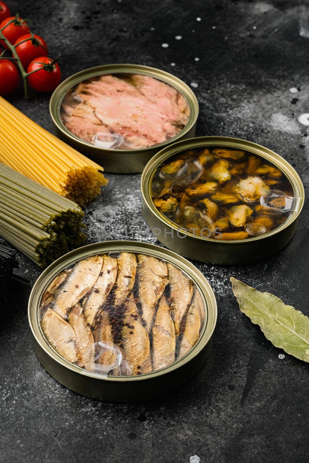 Opened cans with sardines, mussel, tuna set, on black dark stone table background