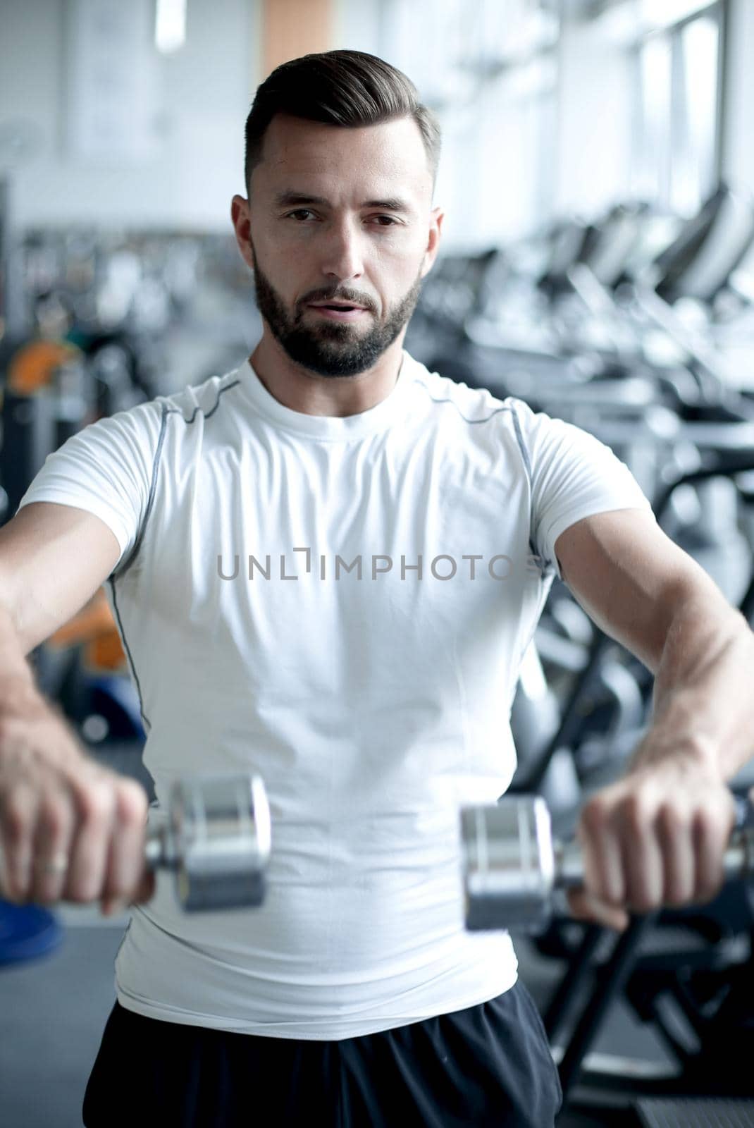close up.stylish young man working with dumbbells in the gym. by asdf