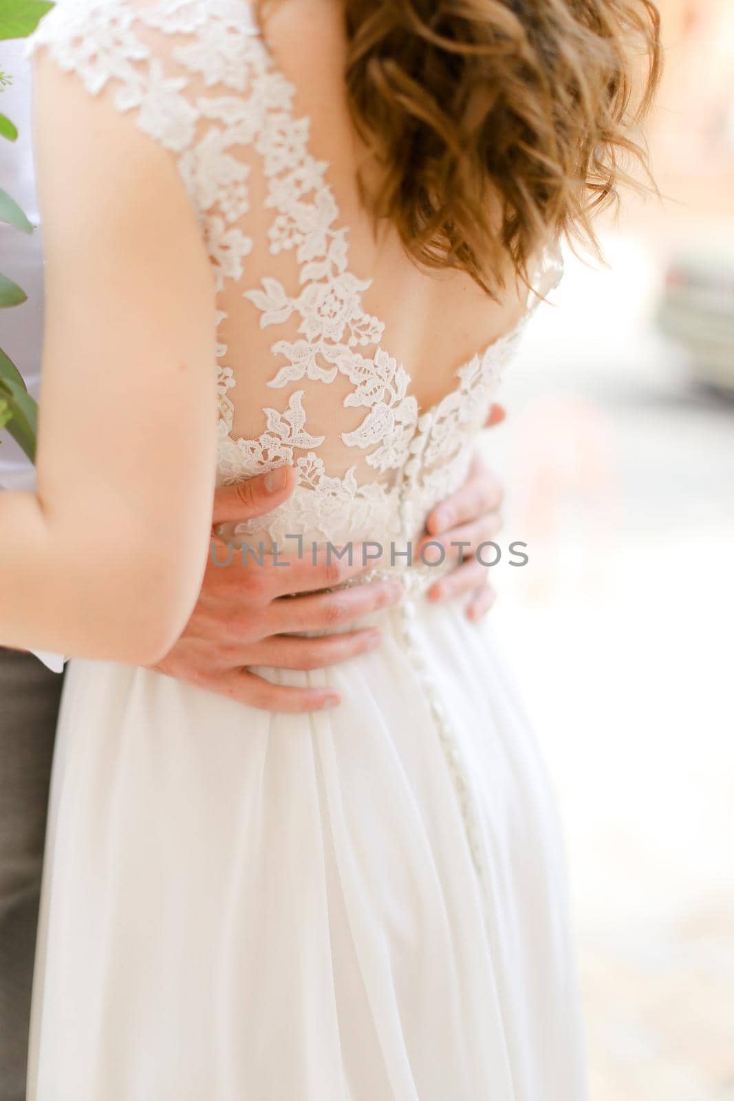 Male hands hugging woman wearing dress. Concept of wedding photo session and tender love.