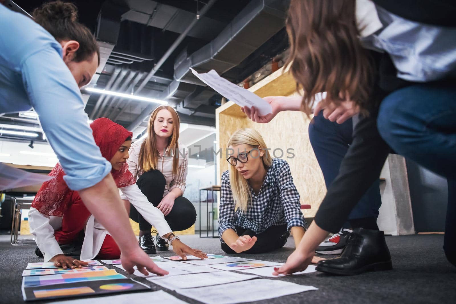 young blonde businesswoman having meeting with her multiethnic startup business team in modern office interior,presenting new ideas on the floor