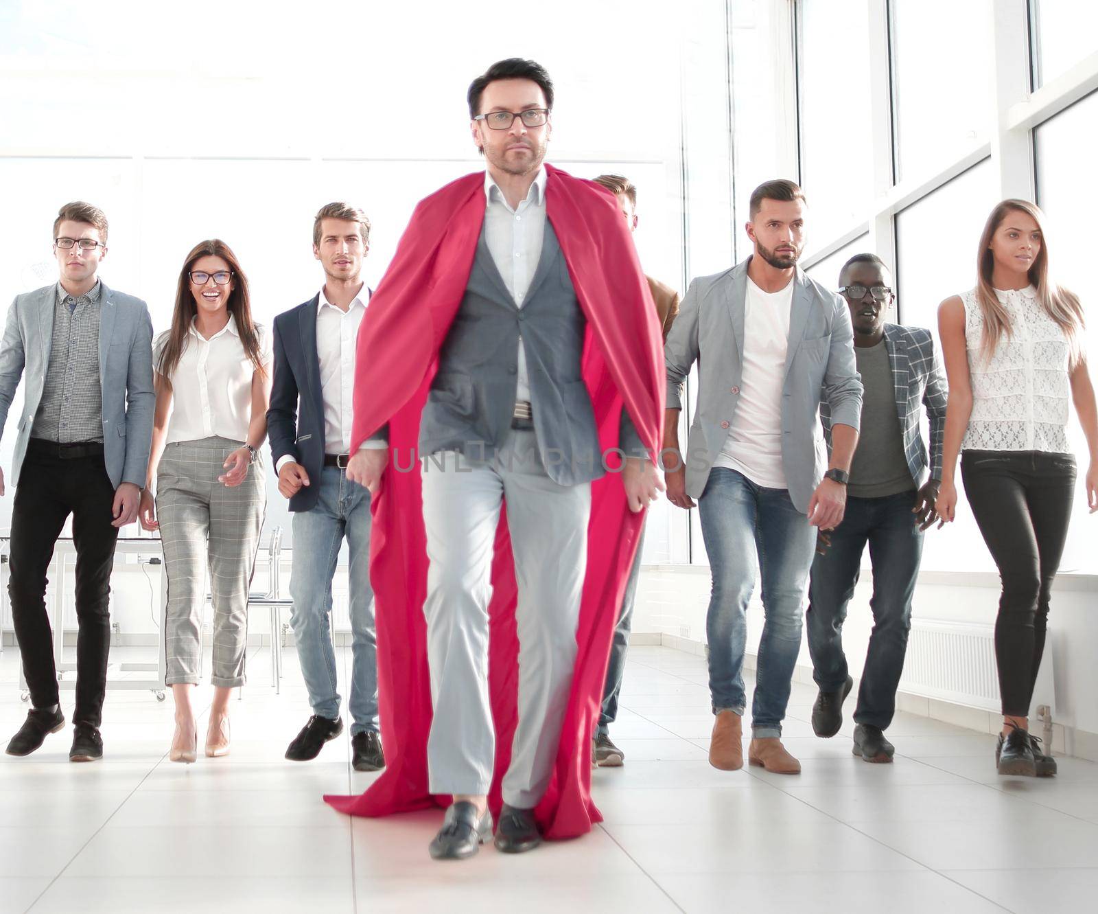 businessman in a superhero's cloak is ahead of the business team by asdf