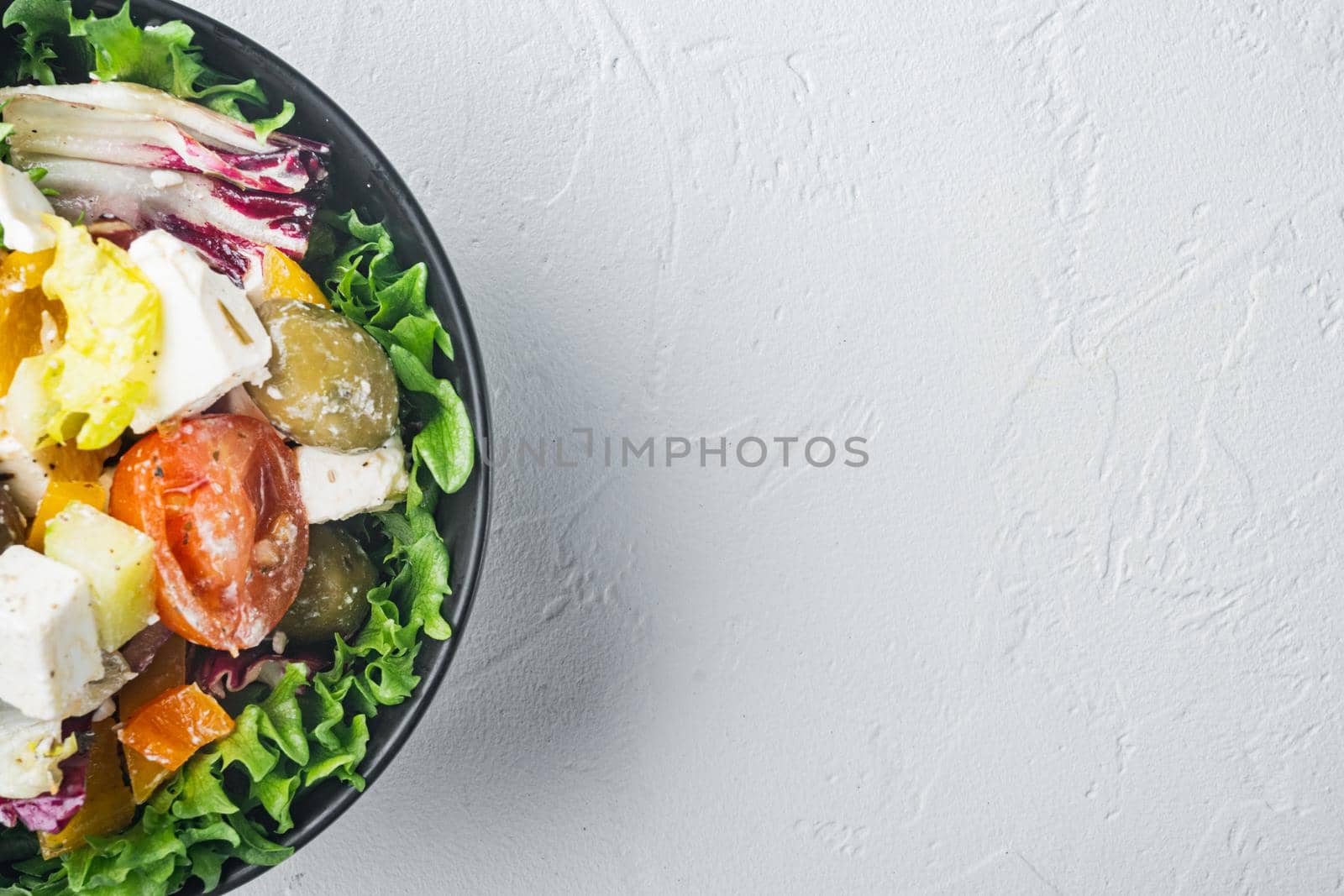 Greek salad with fresh vegetables, feta cheese and olives kalamati, on white background, top view flat lay with copy space for text