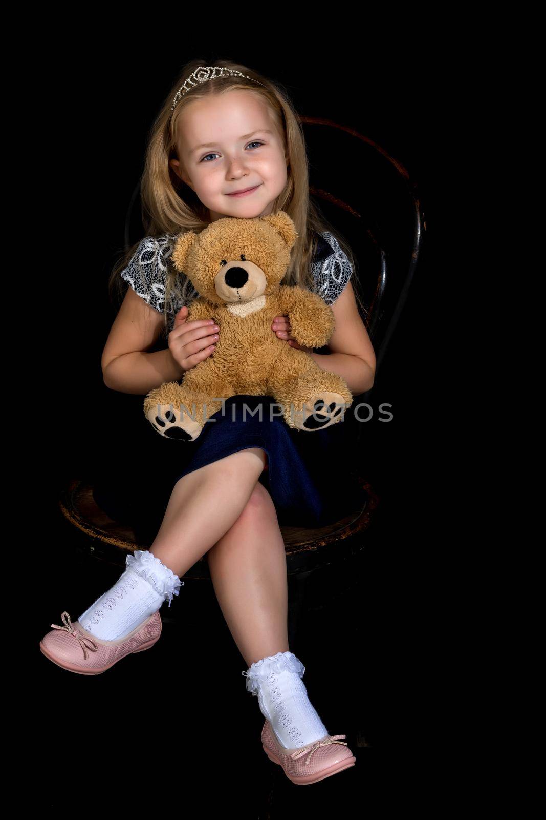 Little girl with a teddy bear on a black background. by kolesnikov_studio