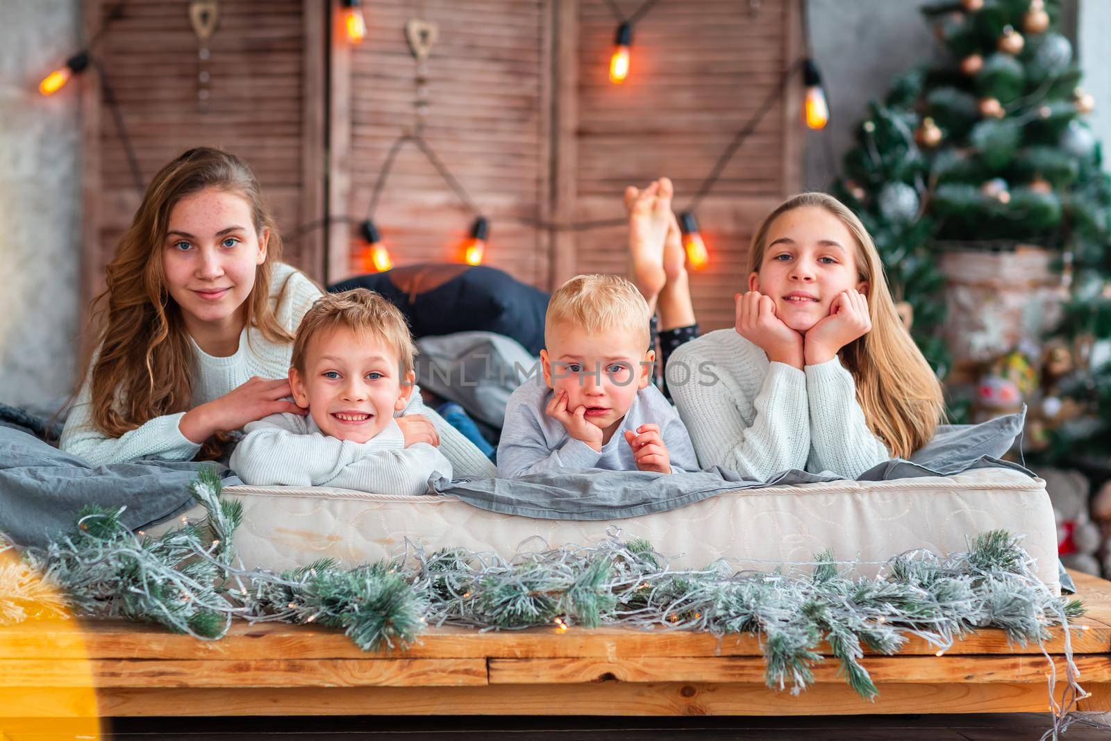 Happy kids siblings having fun on the bed near the Christmas tree on Christmas morning by Len44ik