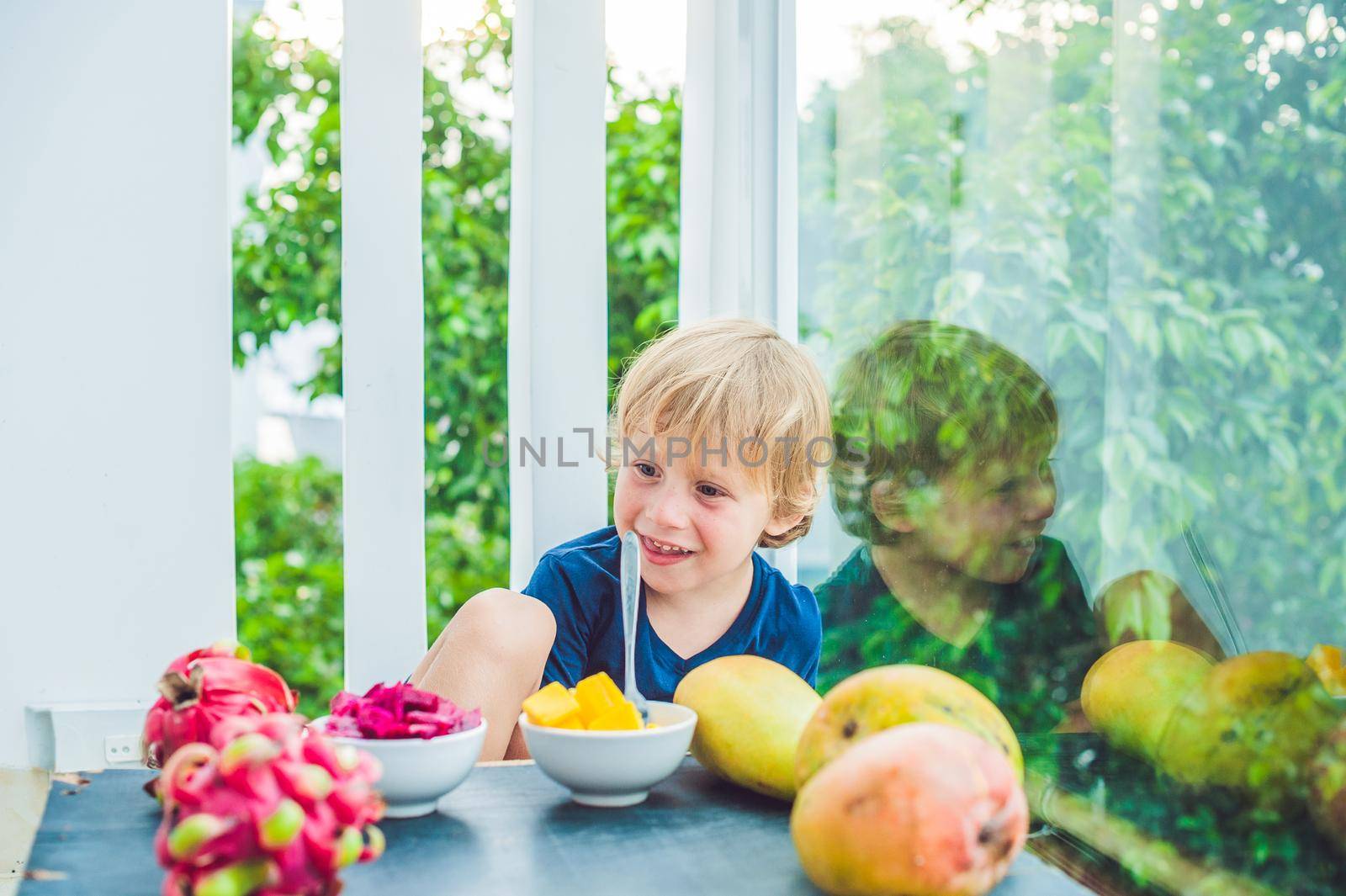 Little cute boy eating mango on the terrace.