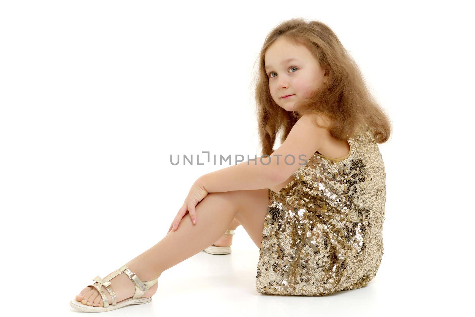 Cute girl posing on the floor in the studio. Hugs his knees. Isolated on white background. The concept of beauty and fashion