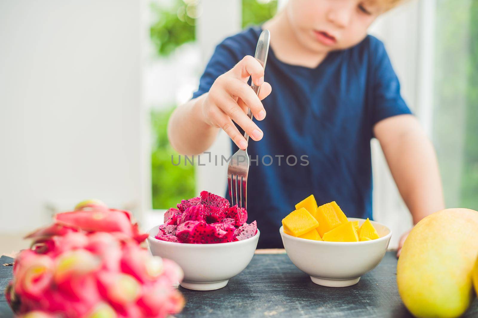 Little cute boy eating mango on the terrace.