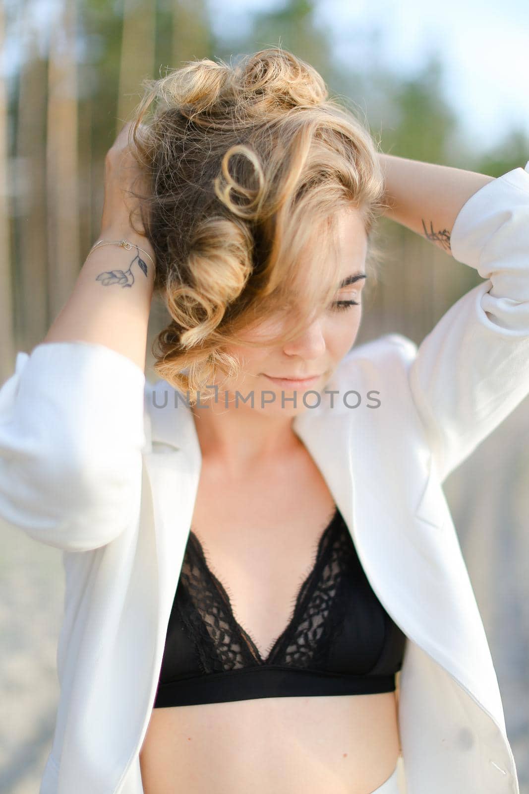 Portraint of young woman with little hand tattoo wearing white shirt and black bra. by sisterspro