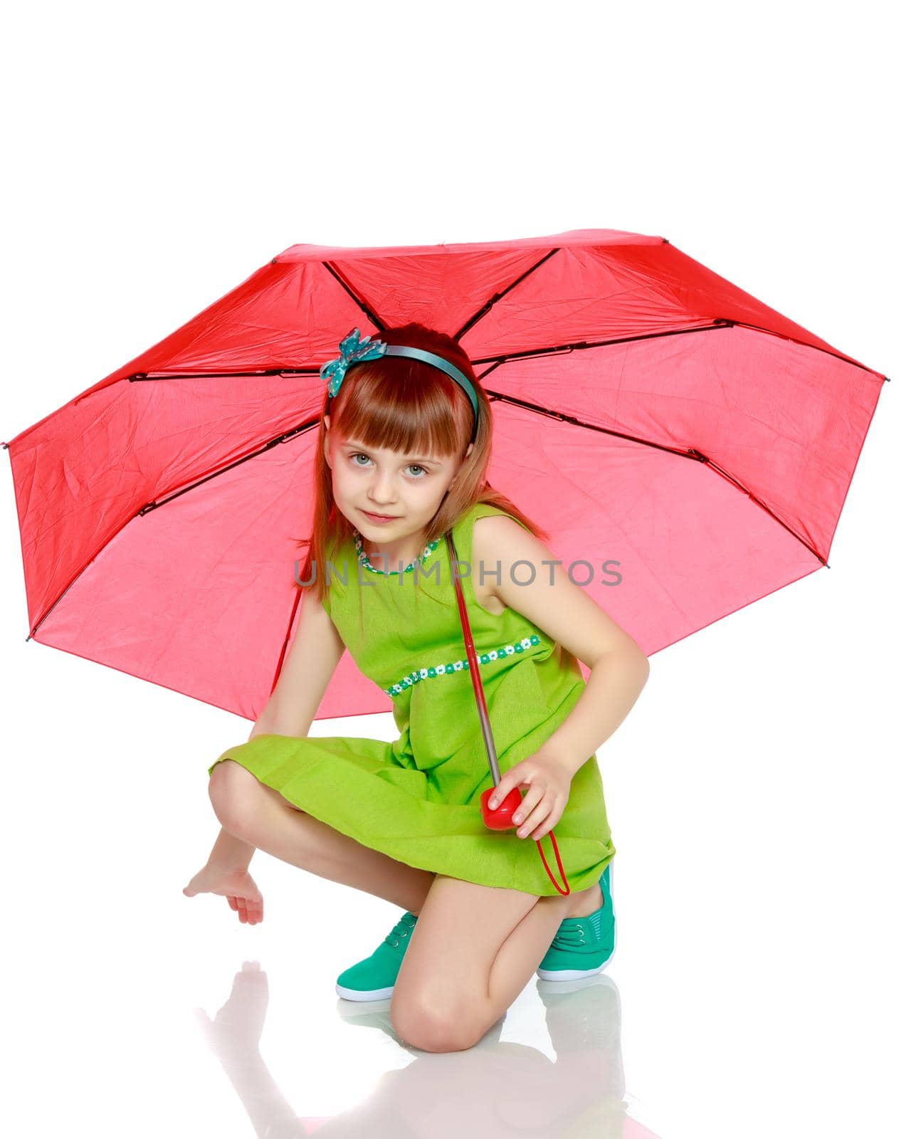 A little girl with long blond hair and a short bangs, in a short summer dress.The girl closed from the sun and rain under a red umbrella.