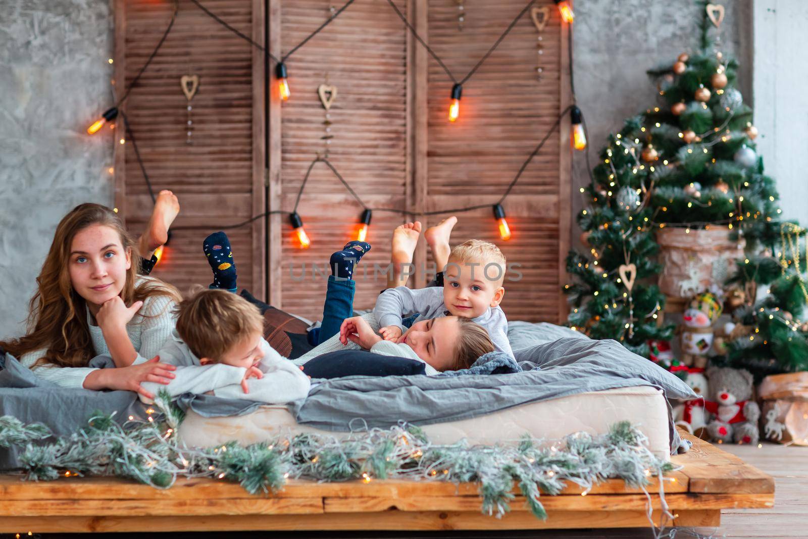 Happy kids siblings having fun on the bed near the Christmas tree on Christmas morning by Len44ik