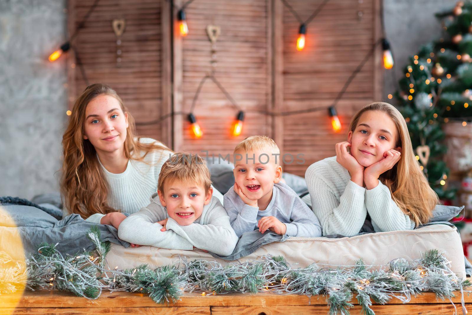 Happy kids siblings having fun on the bed near the Christmas tree on Christmas morning. Christmas family morning, christmas mood concept