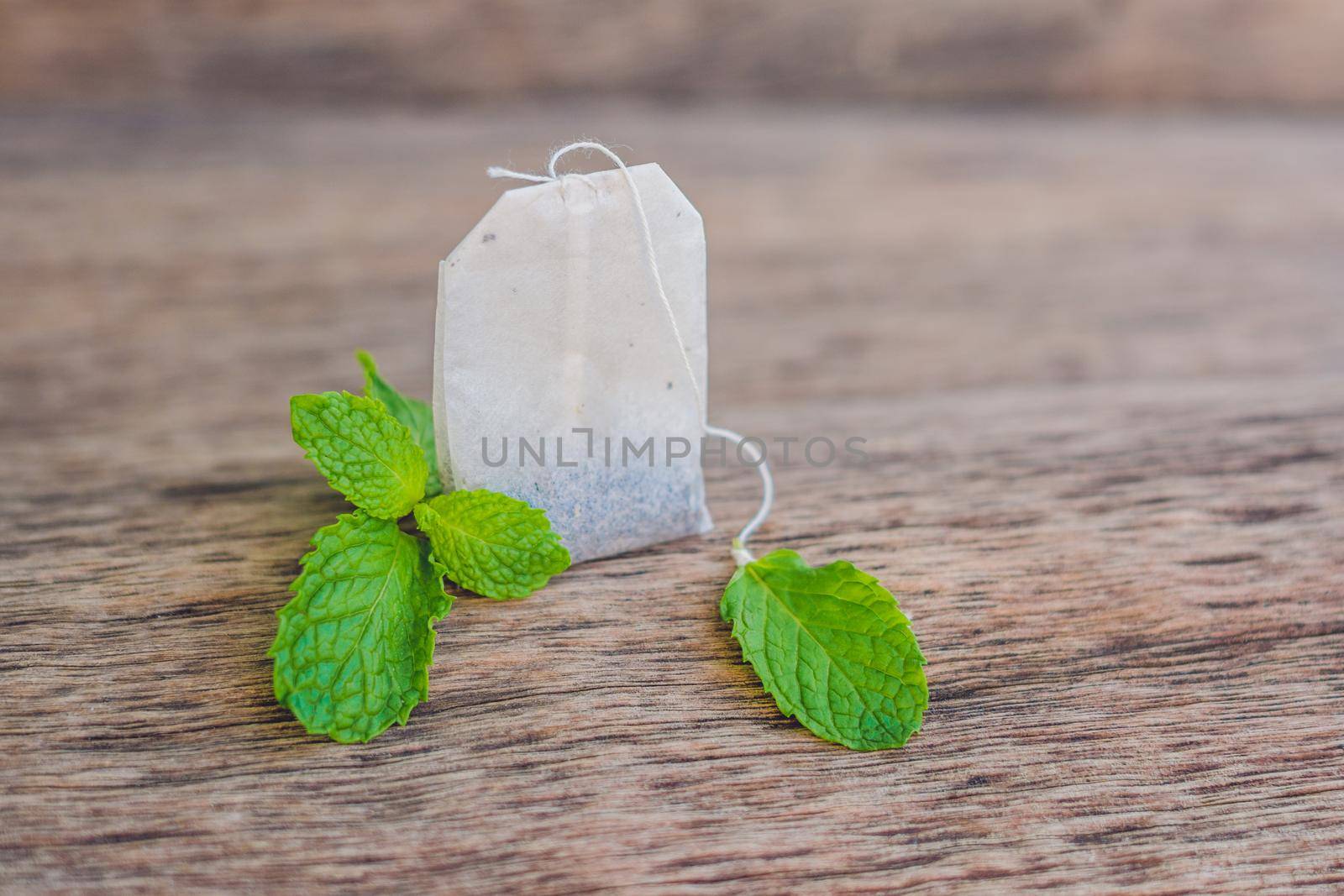 Tea bags on wooden background with fresh melissa, mint. Tea with mint concept.