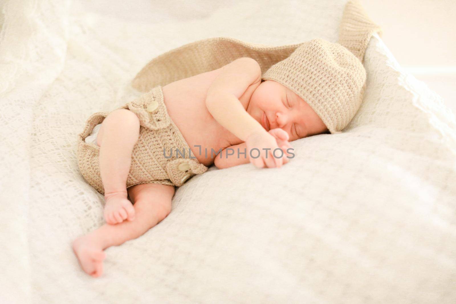 Little newborn baby sleeping and wearing crocheted clothes. by sisterspro