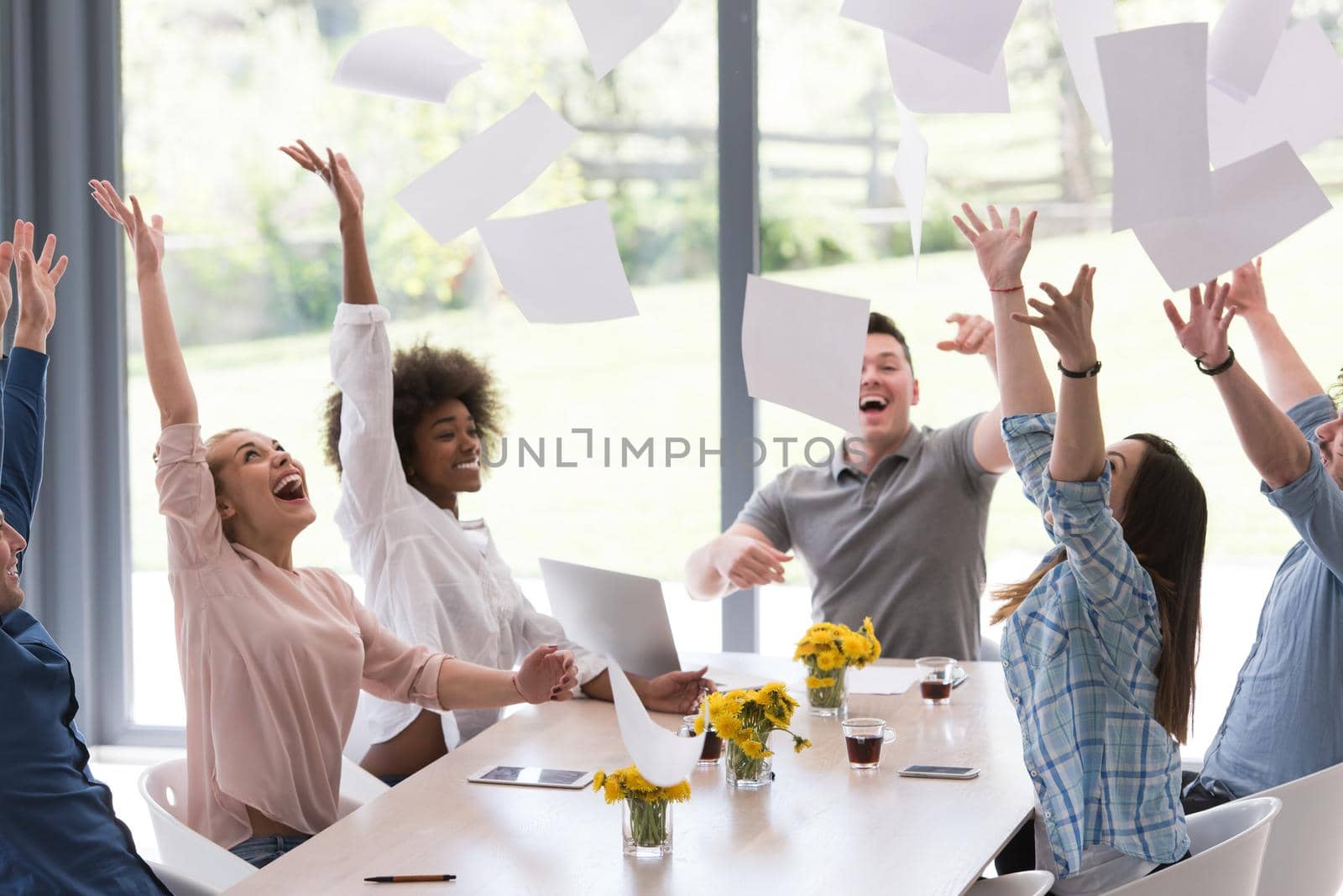 multiethnic Group of young business people throwing documents and looking happy while celebrating success at their working places in startup office