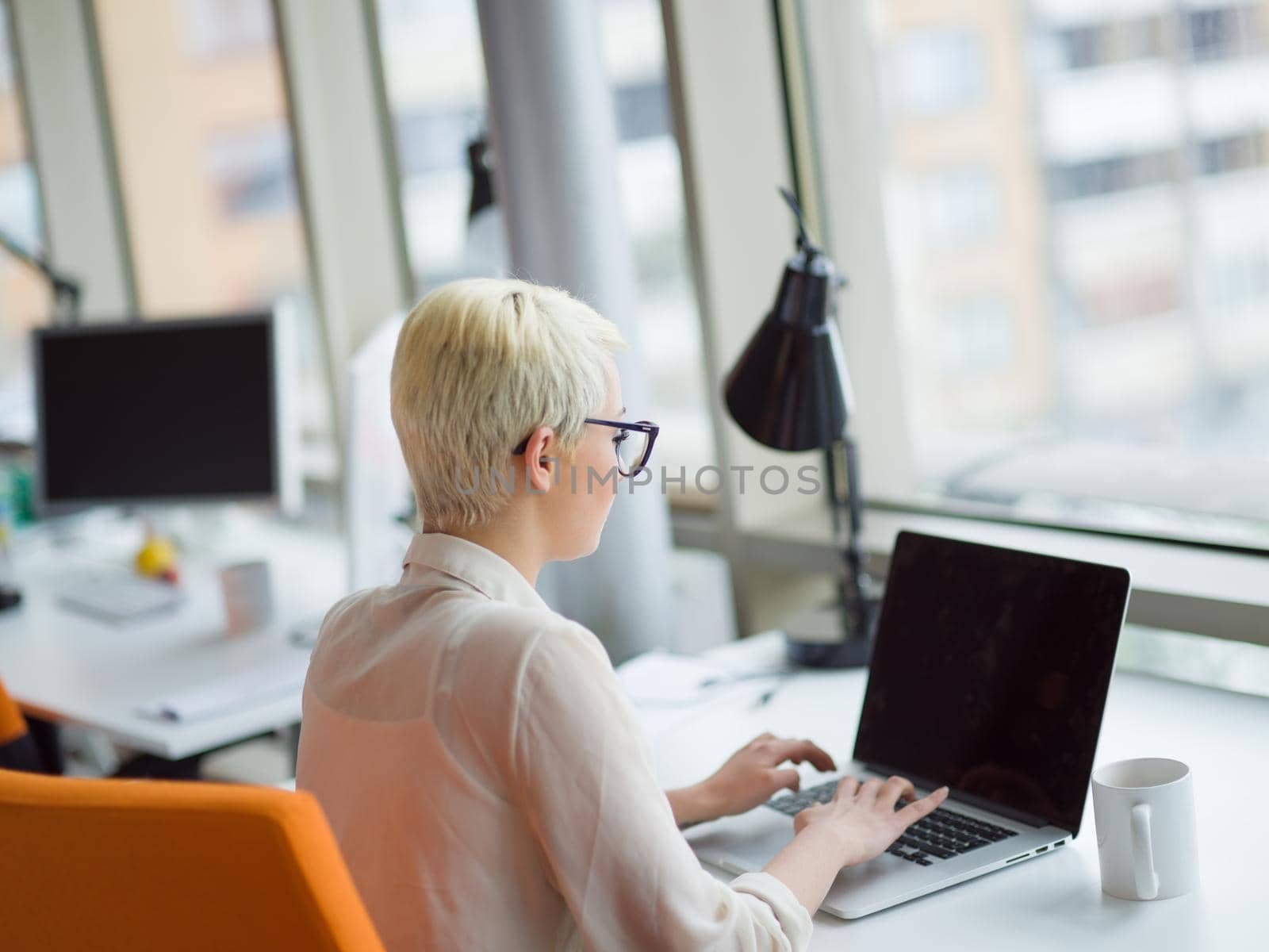businesswoman using a laptop in startup office by dotshock