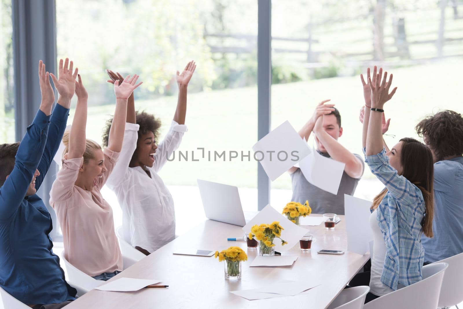multiethnic Group of young business people throwing documents and looking happy while celebrating success at their working places in startup office