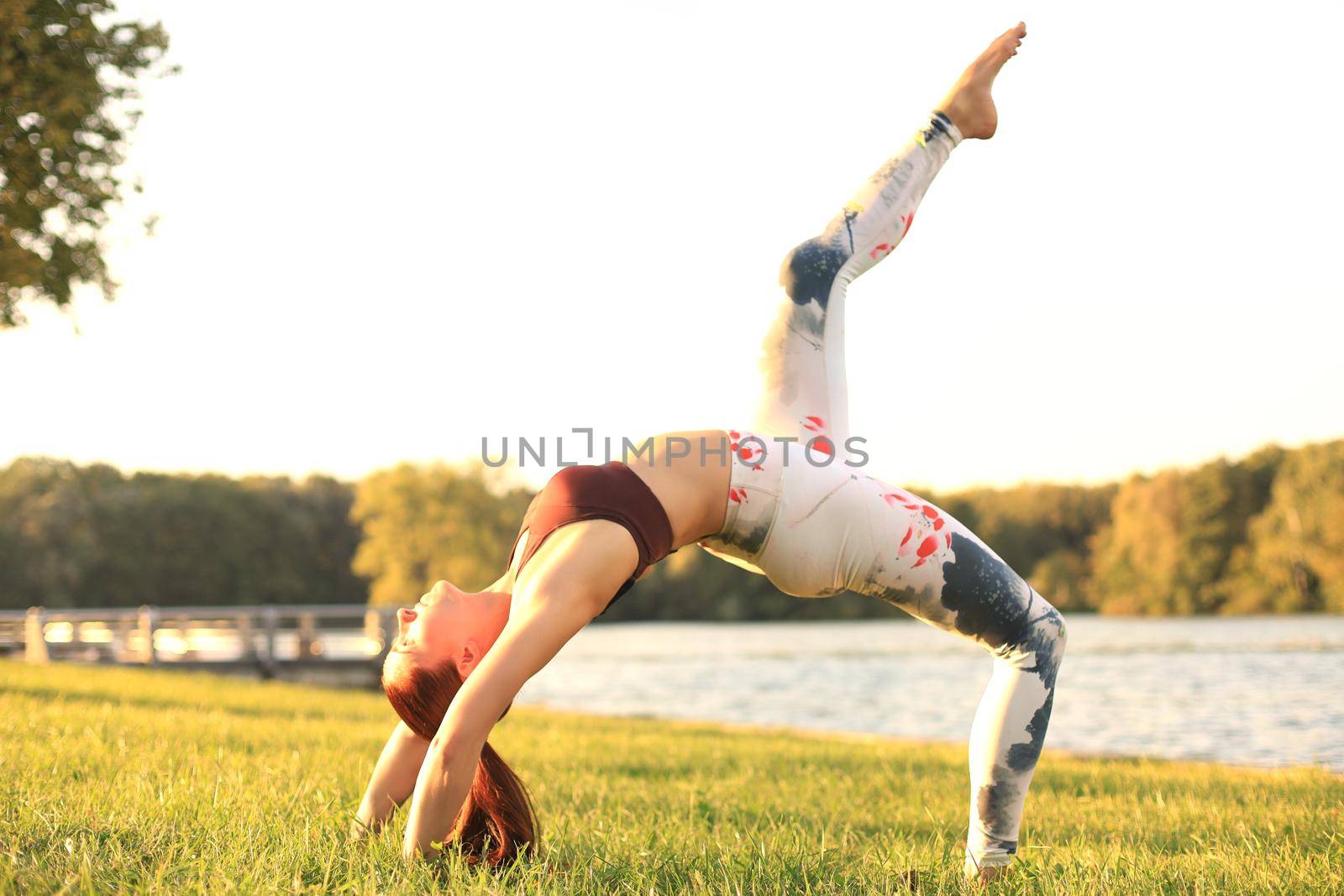 Concentrated pretty strong young redhead sports woman make yoga exercise outdoors. by tsyhun